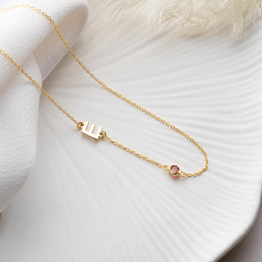 Gold necklace with a small round pendant on a white fabric background