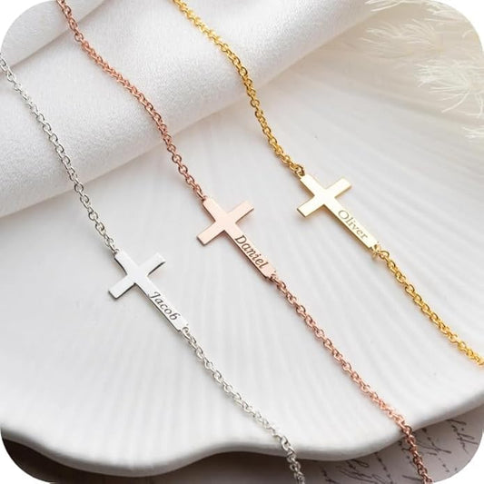 Three cross-shaped necklaces in silver, rose gold, and gold on a white surface.